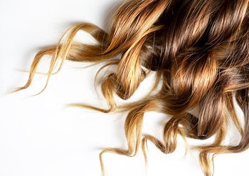 Dunkelblonde gelockte Haarspitzen auf weißem Untergrund