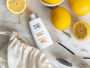 Garnier Sonnenschutz liegt auf einem Tisch voller Zitronen